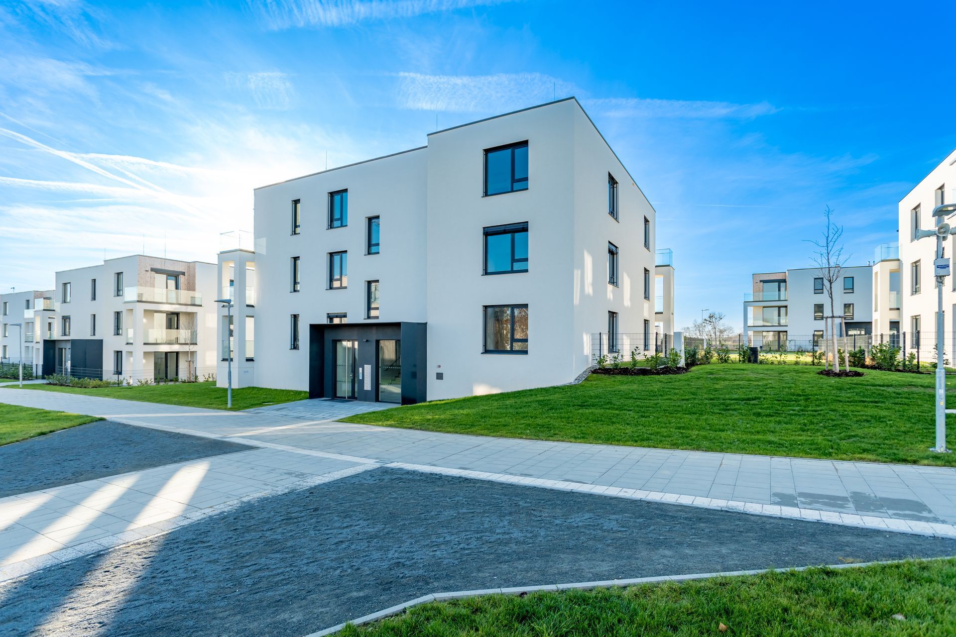 Modern low-rise residential complex with green lawns under a blue sky