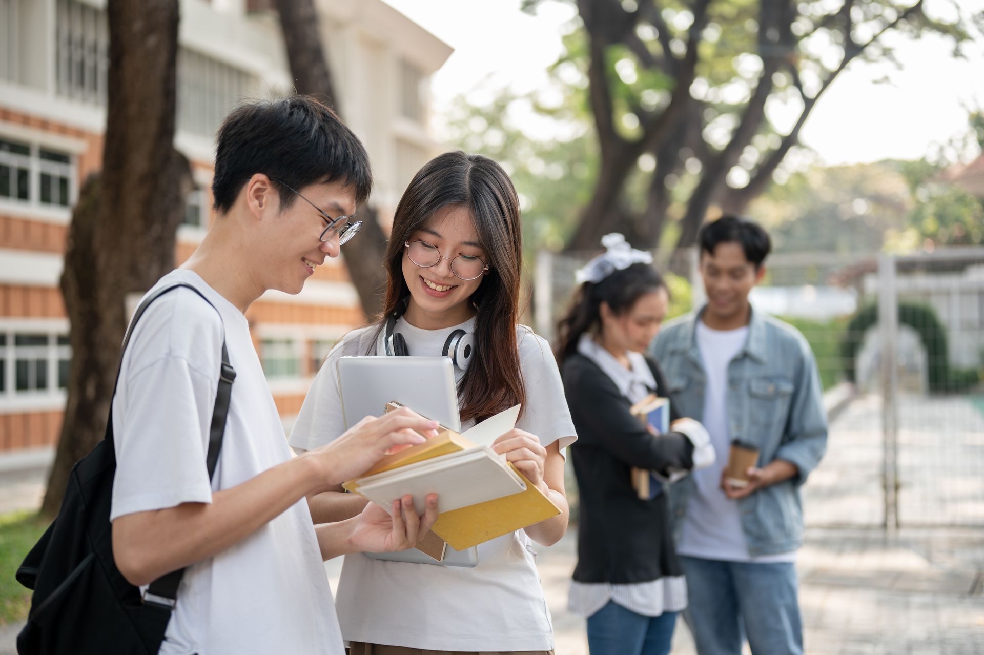Two students reviewing notes together on a campus walkway