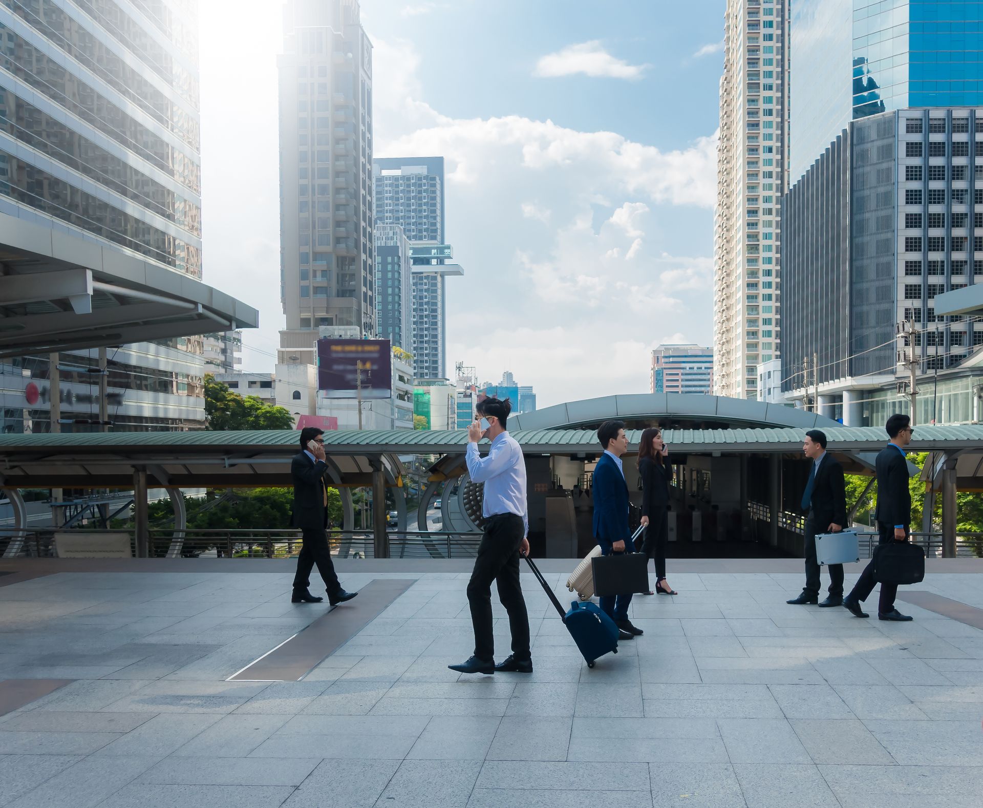 Professionals with luggage crossing a plaza in a modern business district