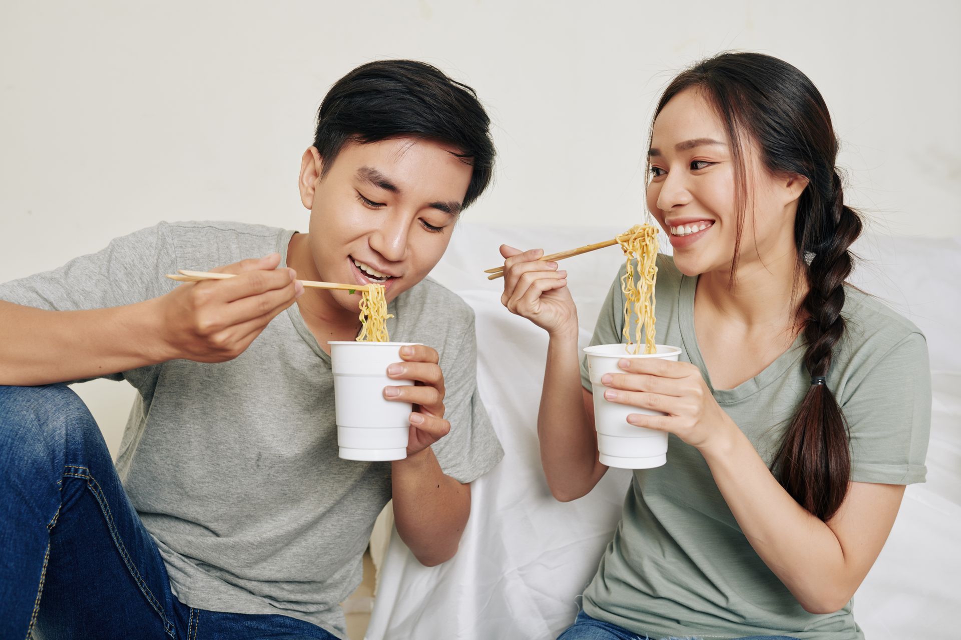 Young couple happily eating instant noodles together