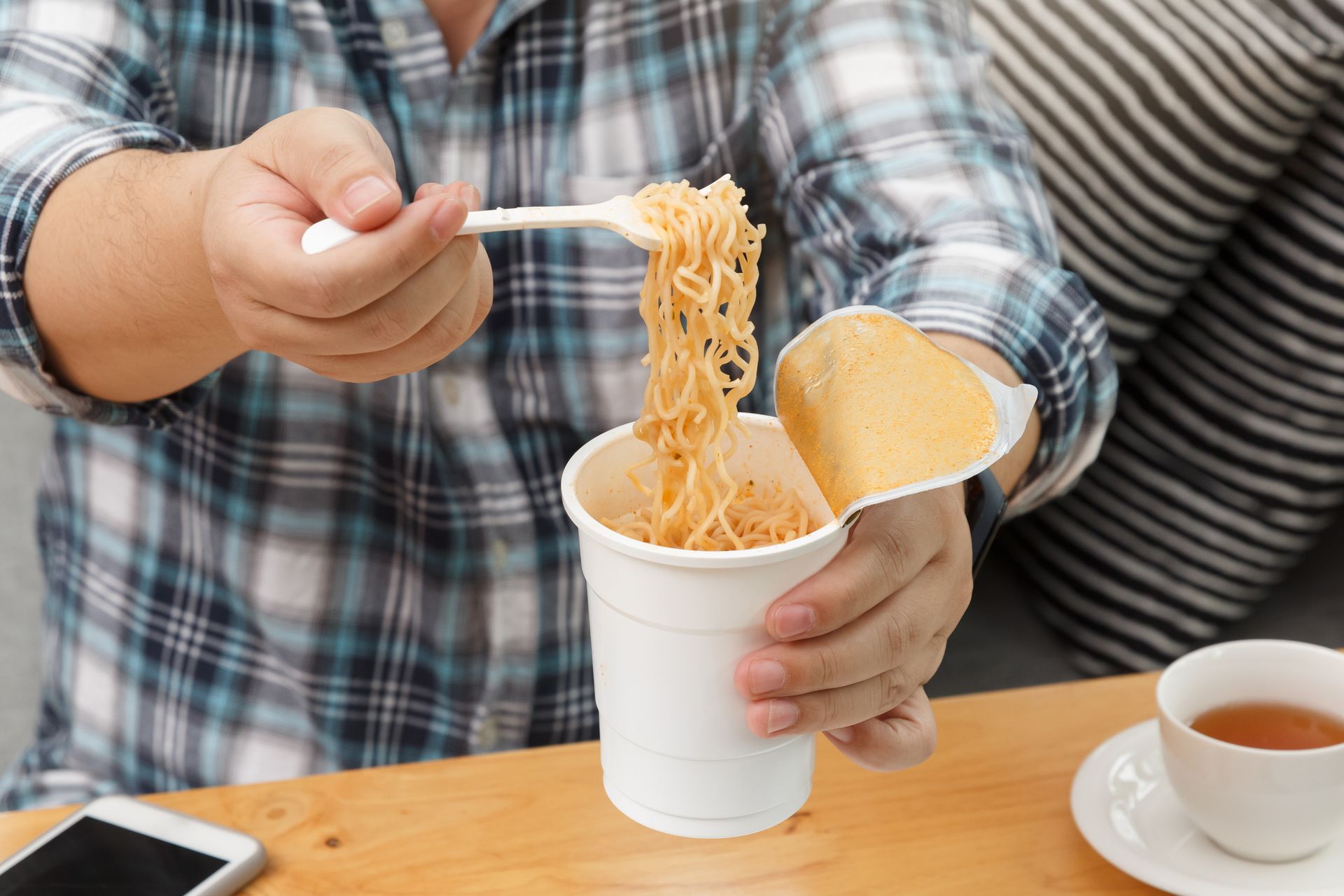 Young couple happily eating instant noodles together