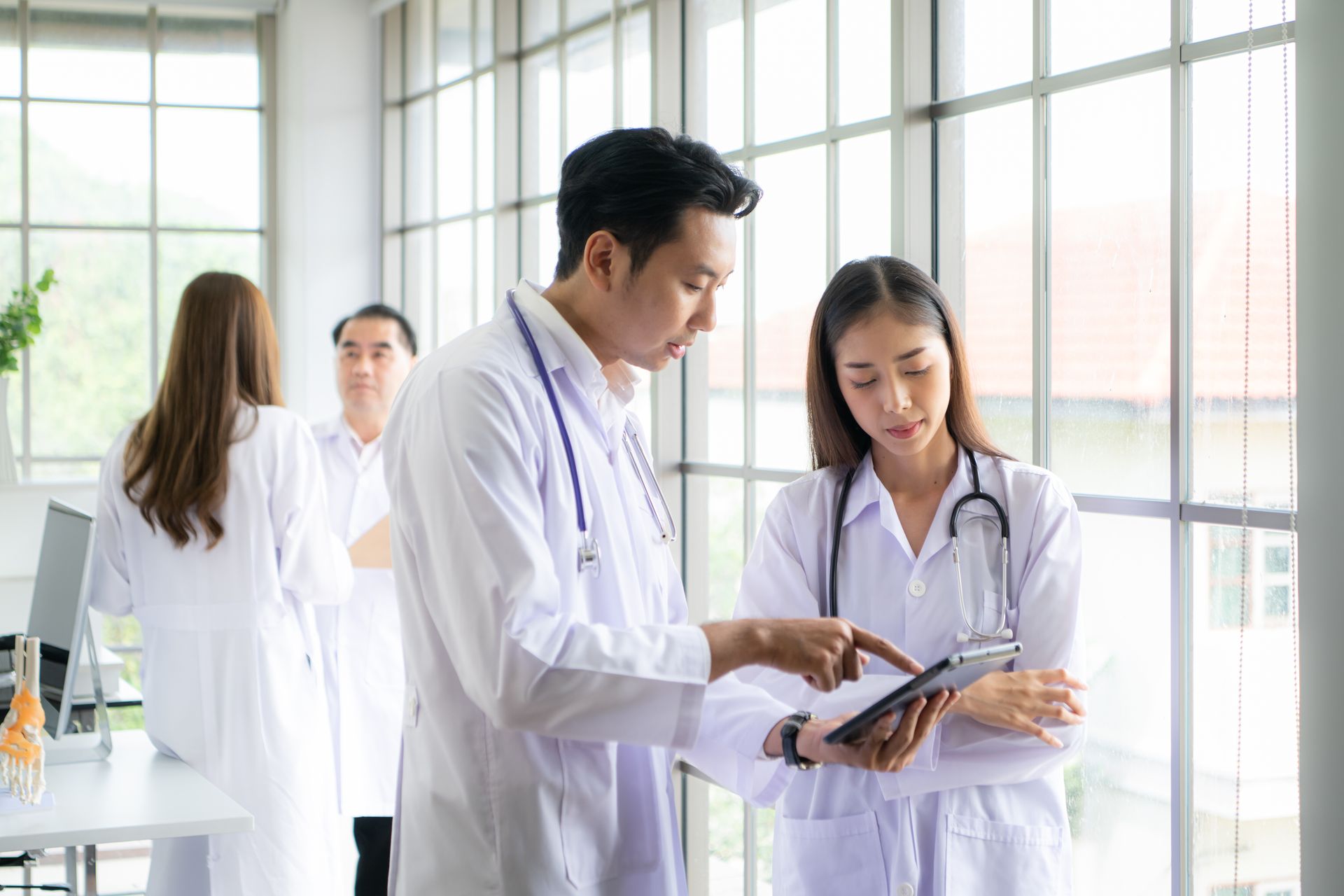 Two doctors reviewing a tablet together in a bright hospital