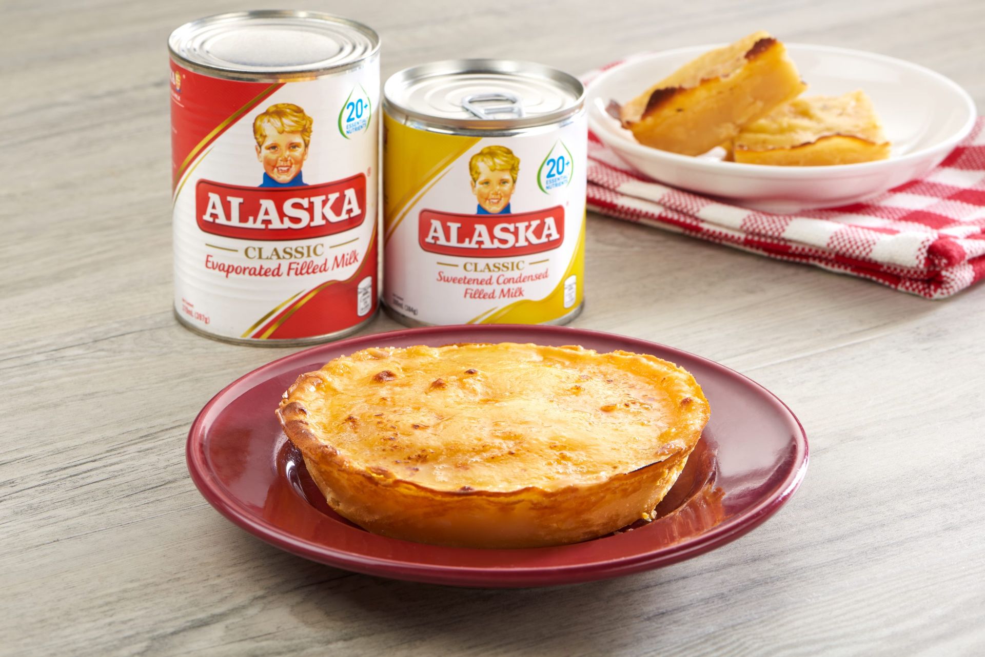 Alaska evaporated and condensed milk cans beside a baked leche flan