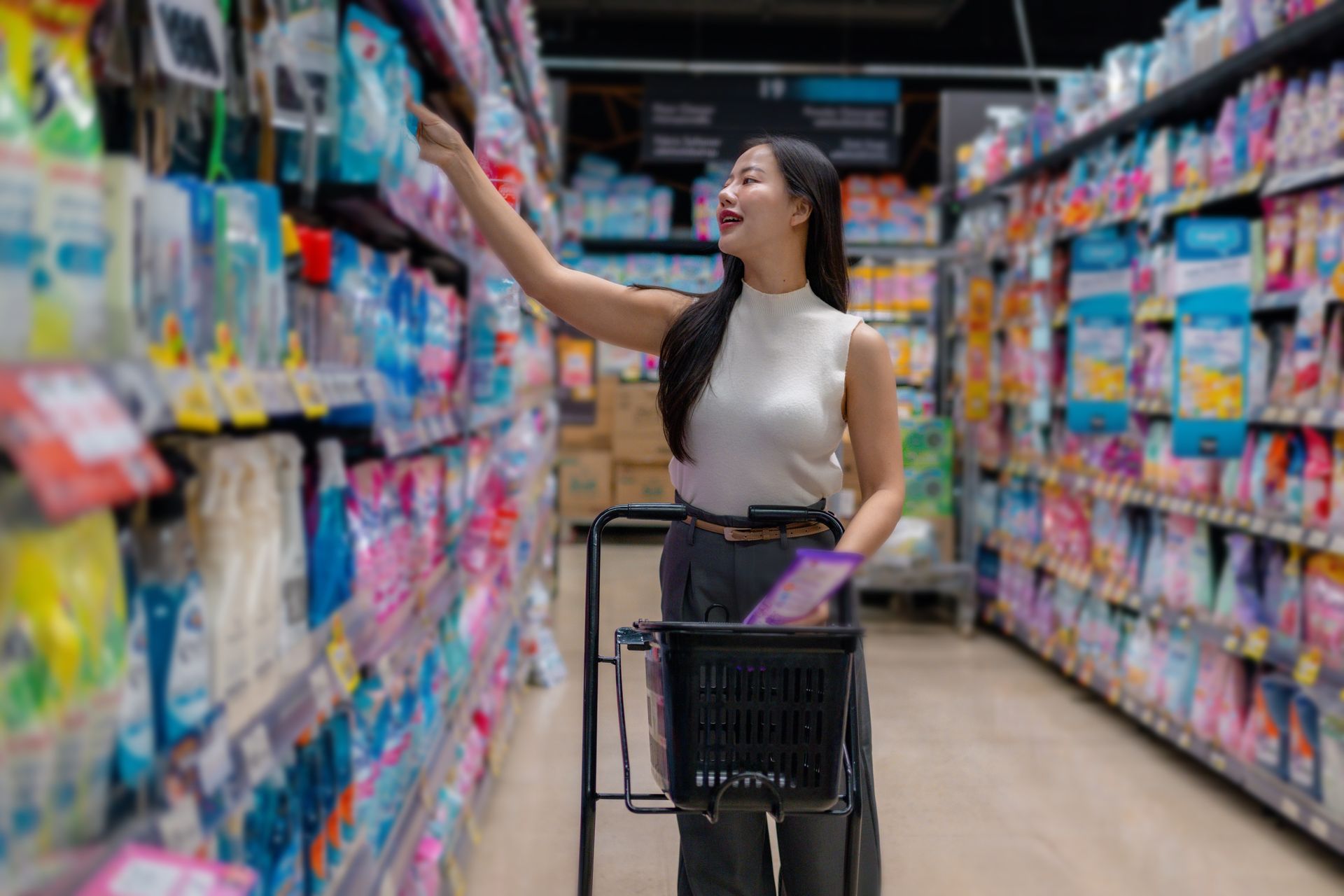 Woman comparing two cleaning product bottles in a supermarket aisle