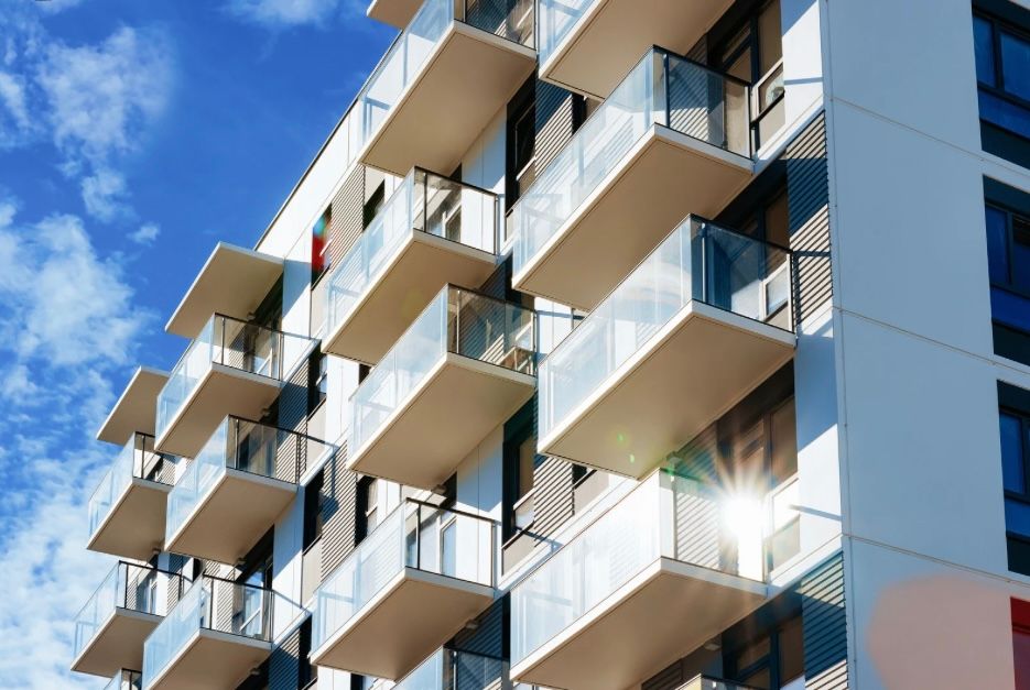 Modern multi-story residential building with balconies against a blue sky