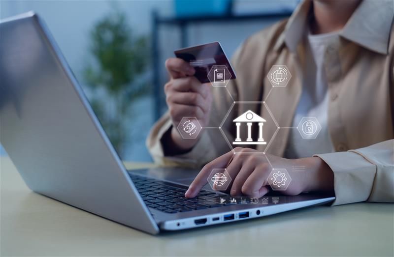Hand holding a card and phone with digital finance icons and house models
