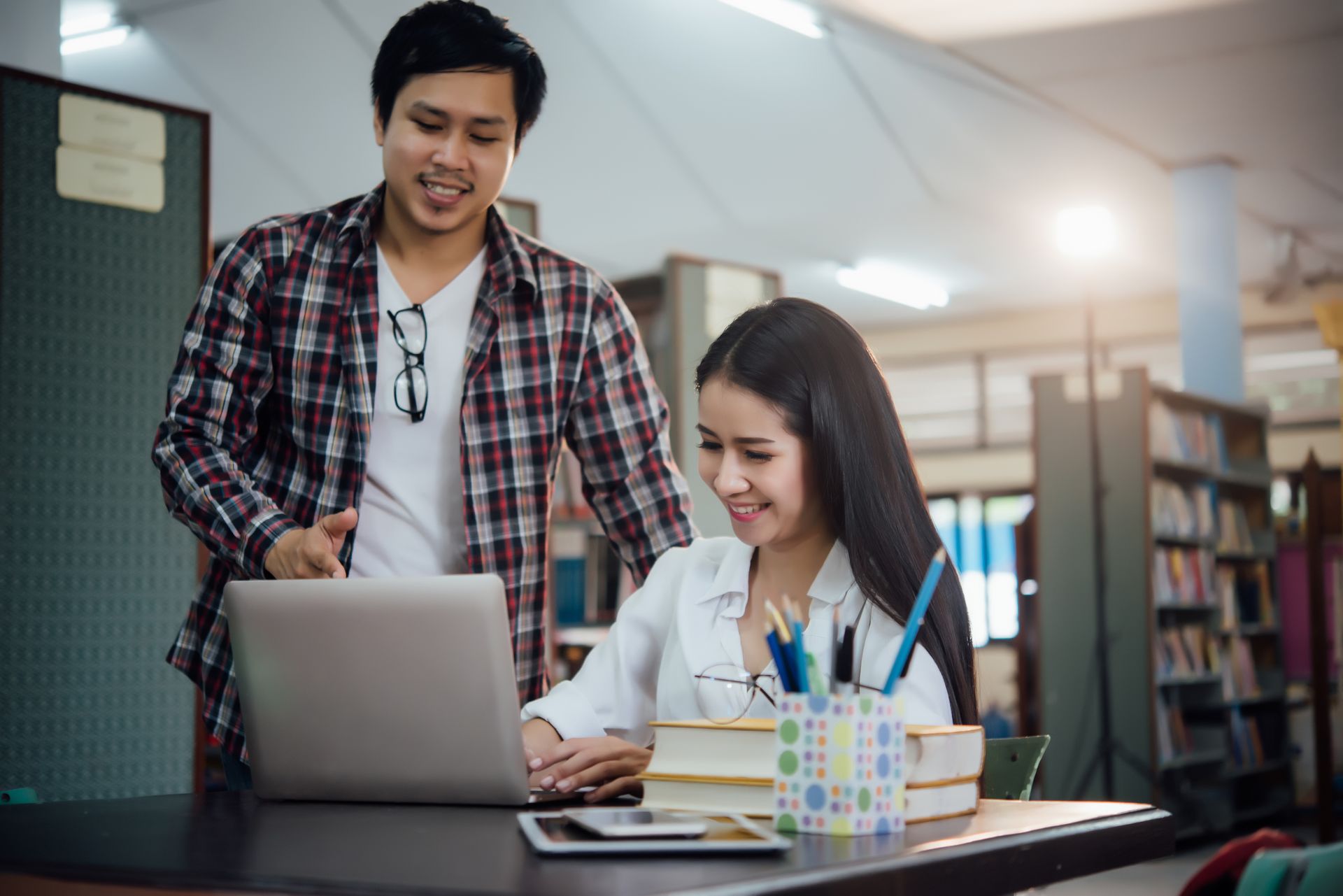 Two students reviewing notes together on a campus walkway