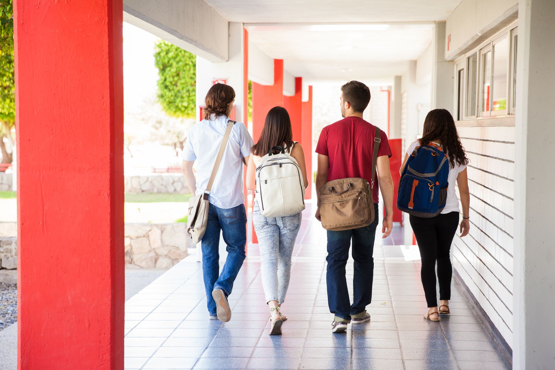 Students with backpacks walking down a covered school hallway