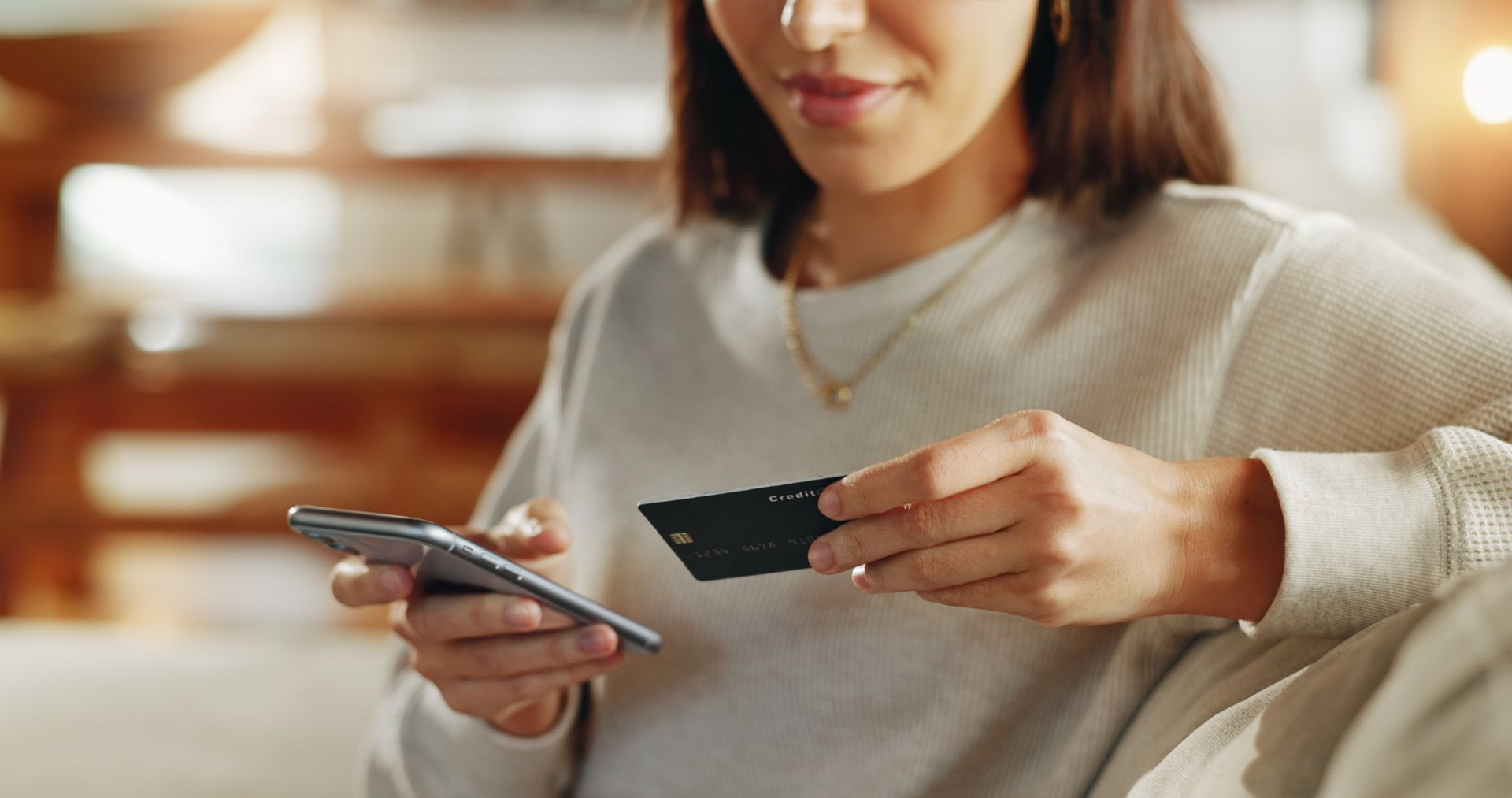 Woman holding a payment card and phone while shopping online