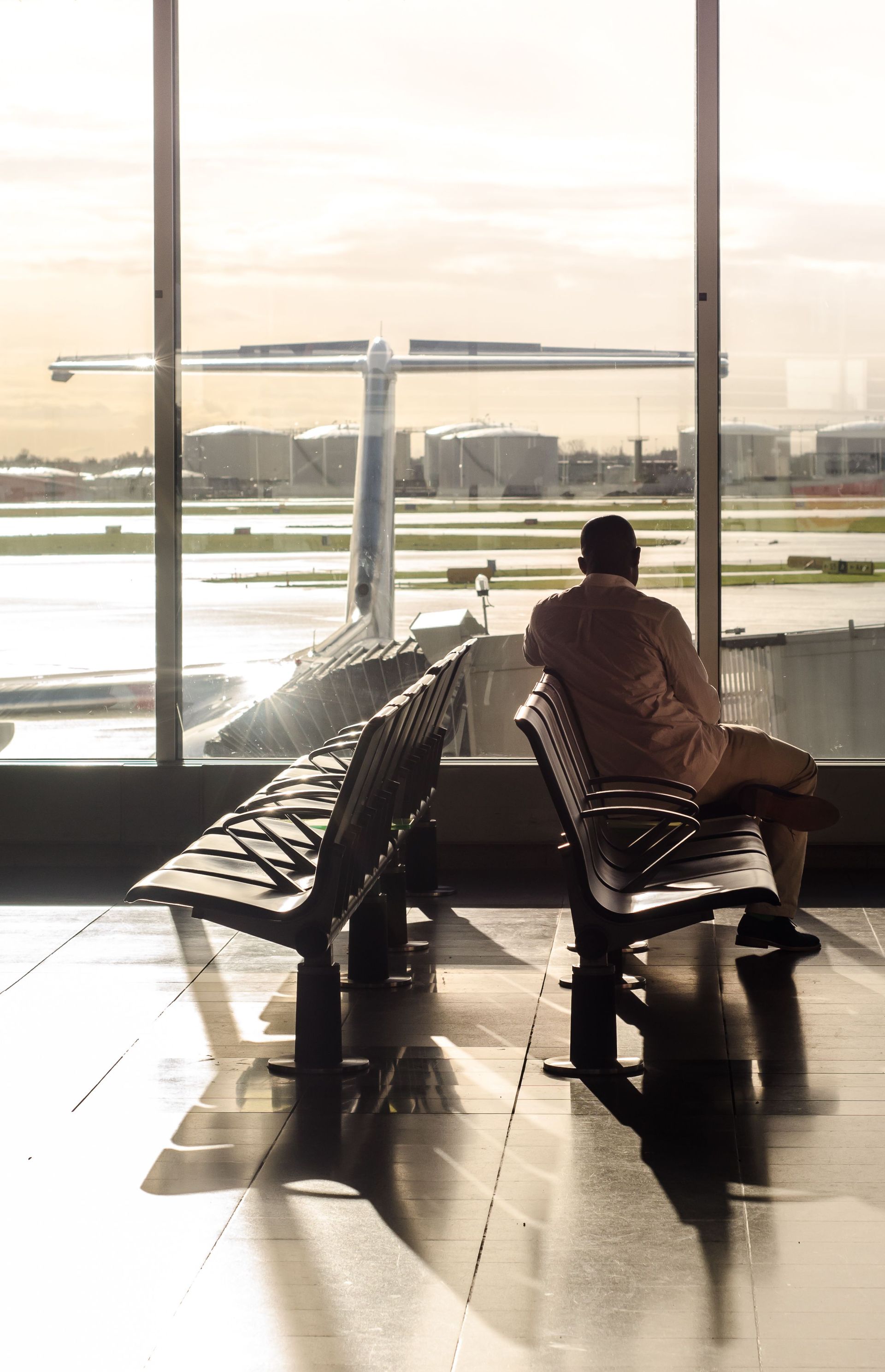 Traveler seated alone at an airport gate watching planes through the window