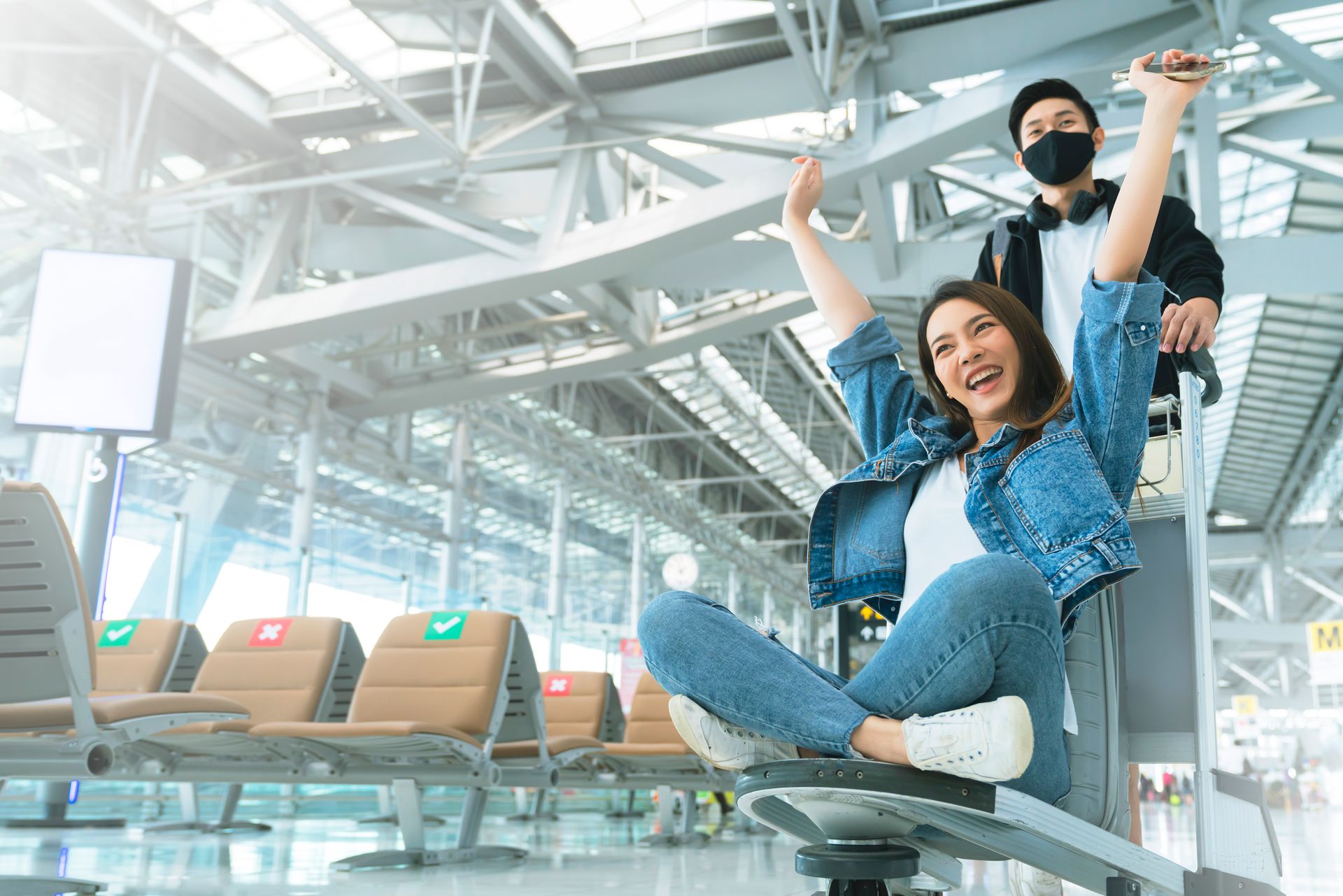 Smiling woman checking her phone while holding a passport in a terminal