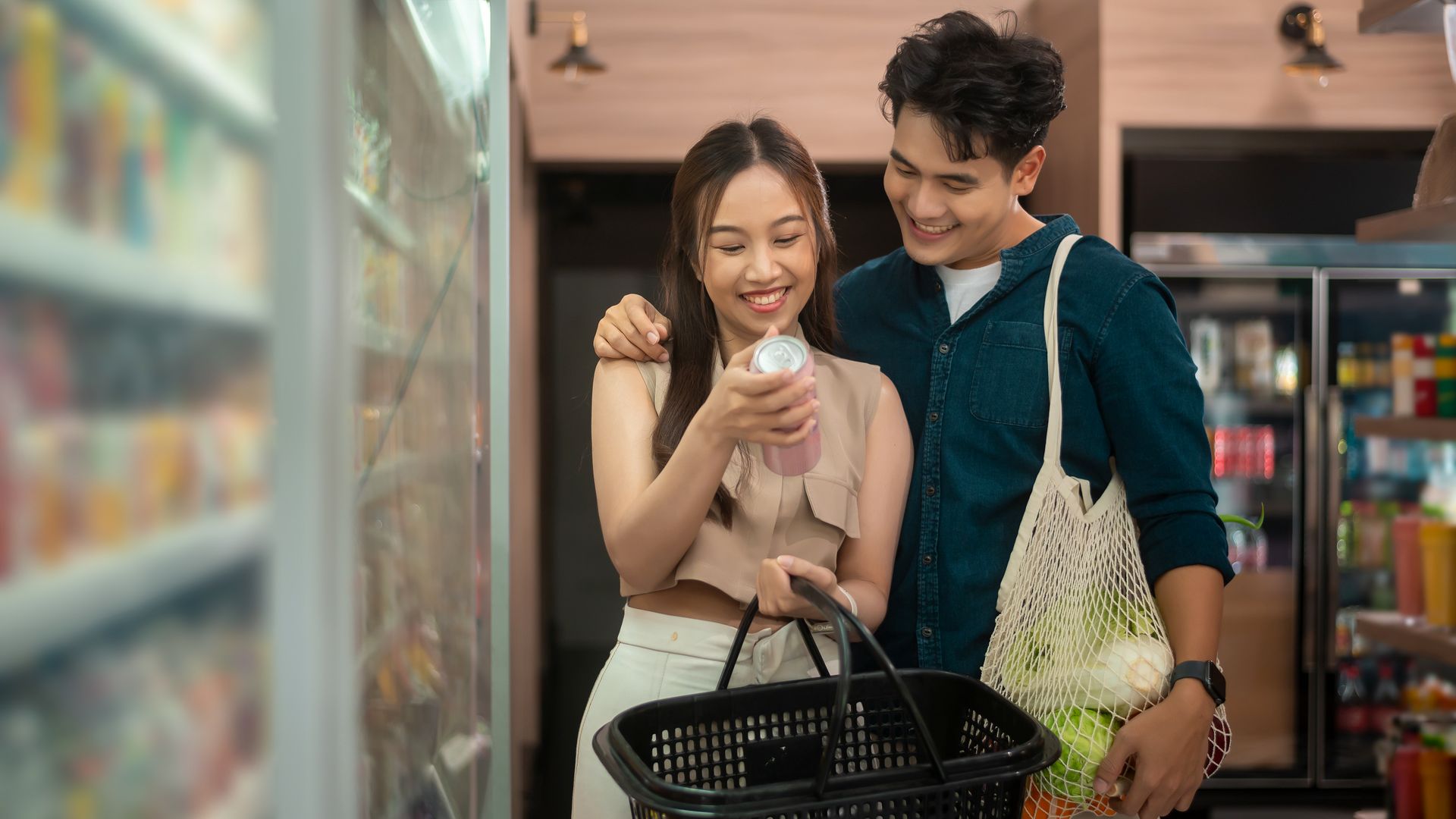 Two women with a shopping basket browsing products in a store aisle