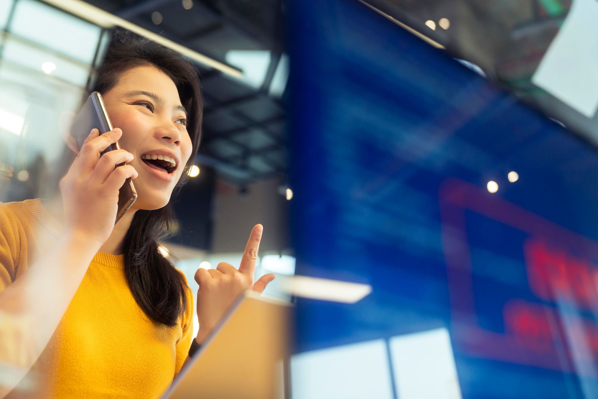 Smiling woman on her phone pointing at an information board