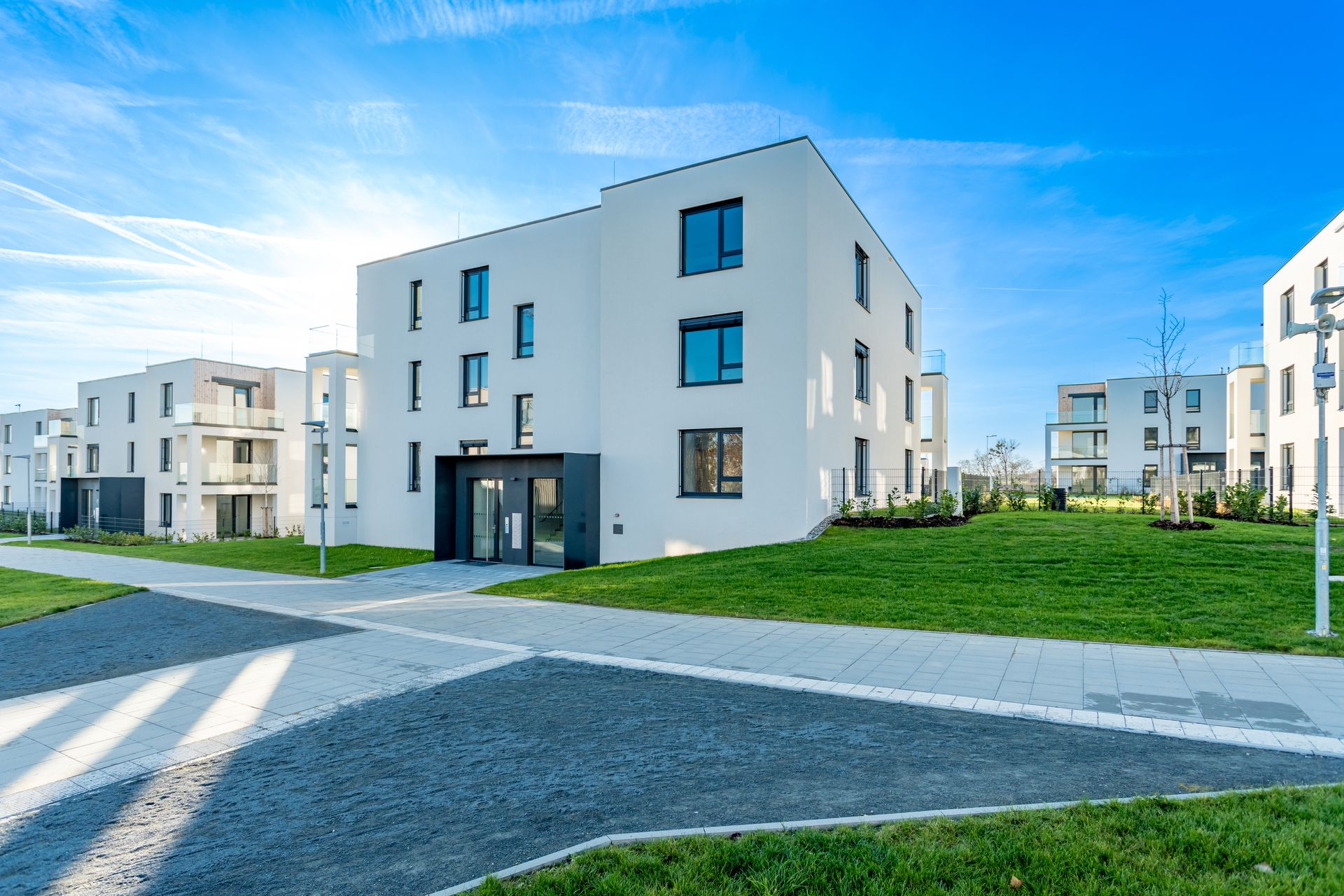 Modern low-rise residential complex with green lawns under a blue sky