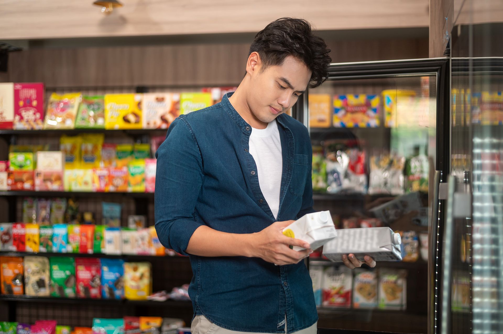 Shopper with a basket selecting products from a supermarket shelf