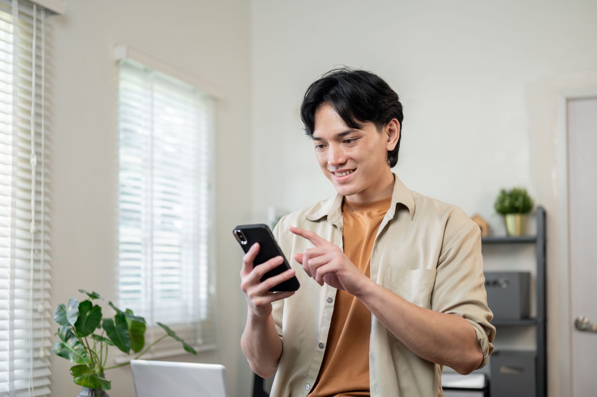 Young man smiling while using his smartphone at home