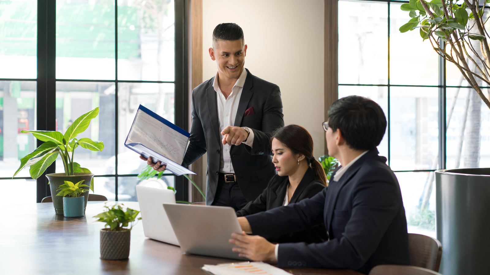 Diverse team collaborating around a table with charts and code screens in a modern office