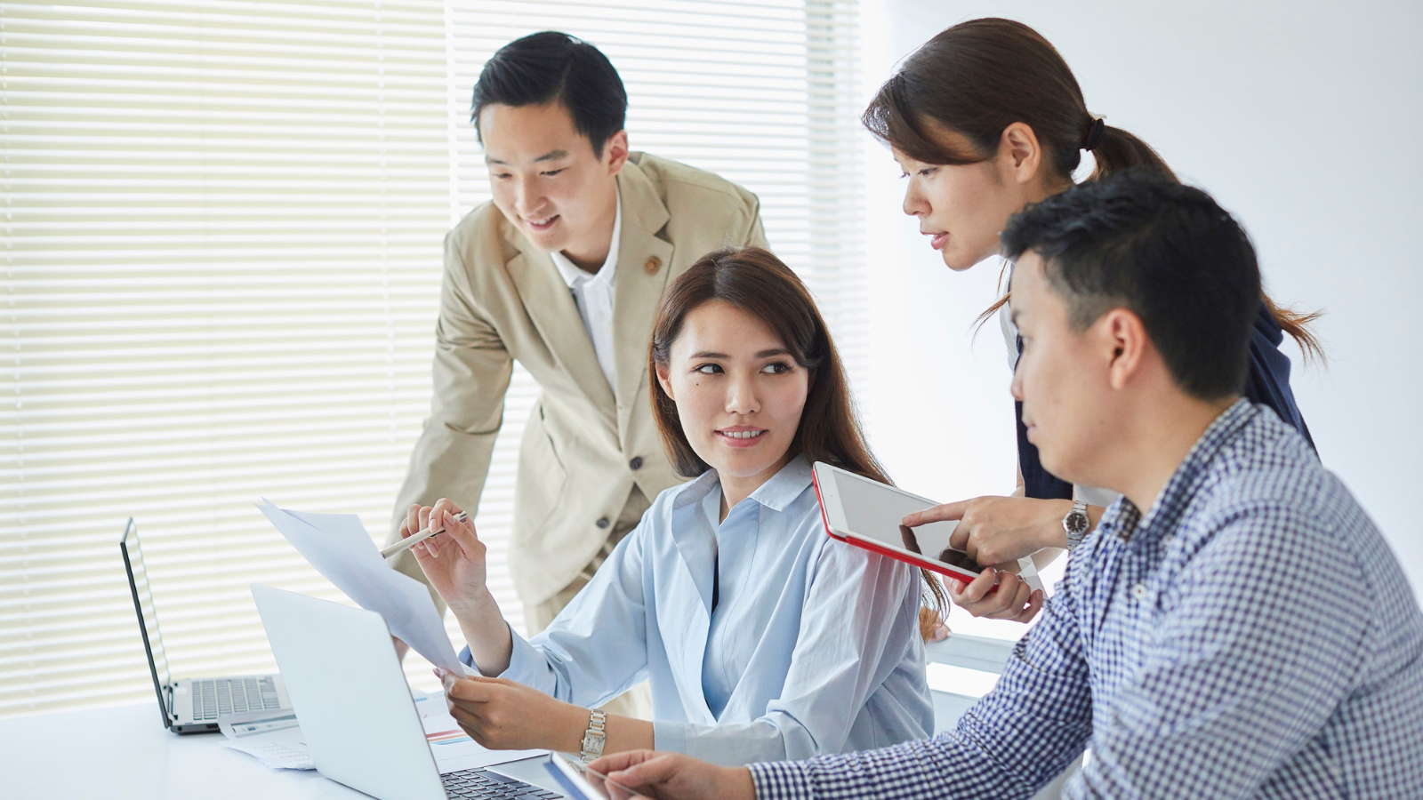 Diverse team collaborating around a table with charts and code screens in a modern office