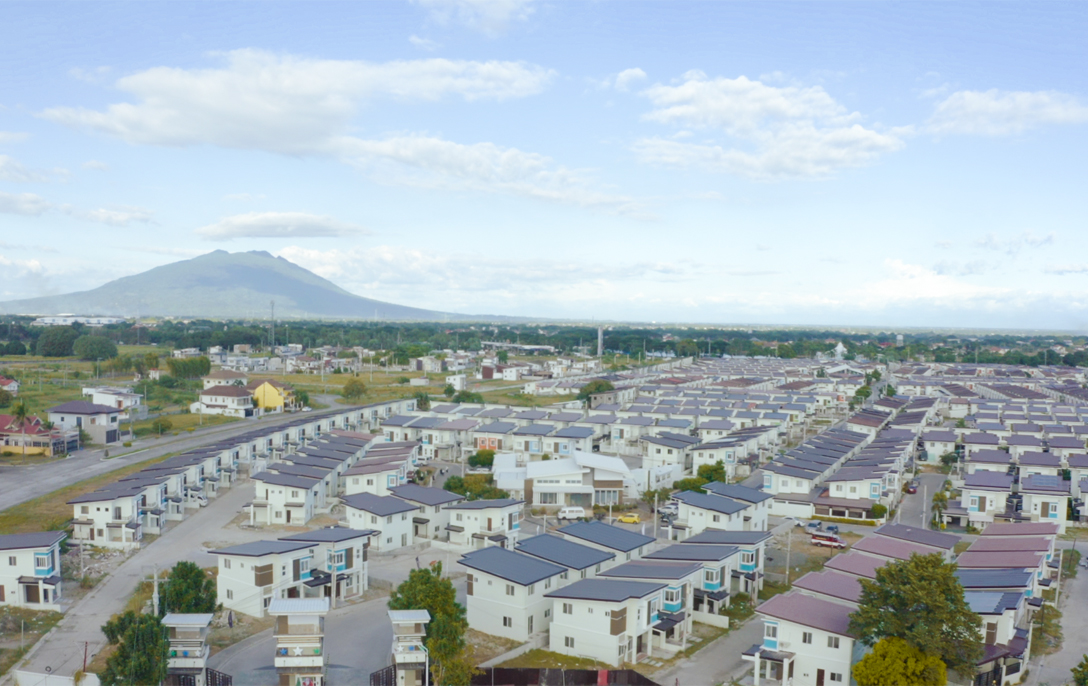 Aerial view of a large residential subdivision with rows of houses and a mountain in the distance