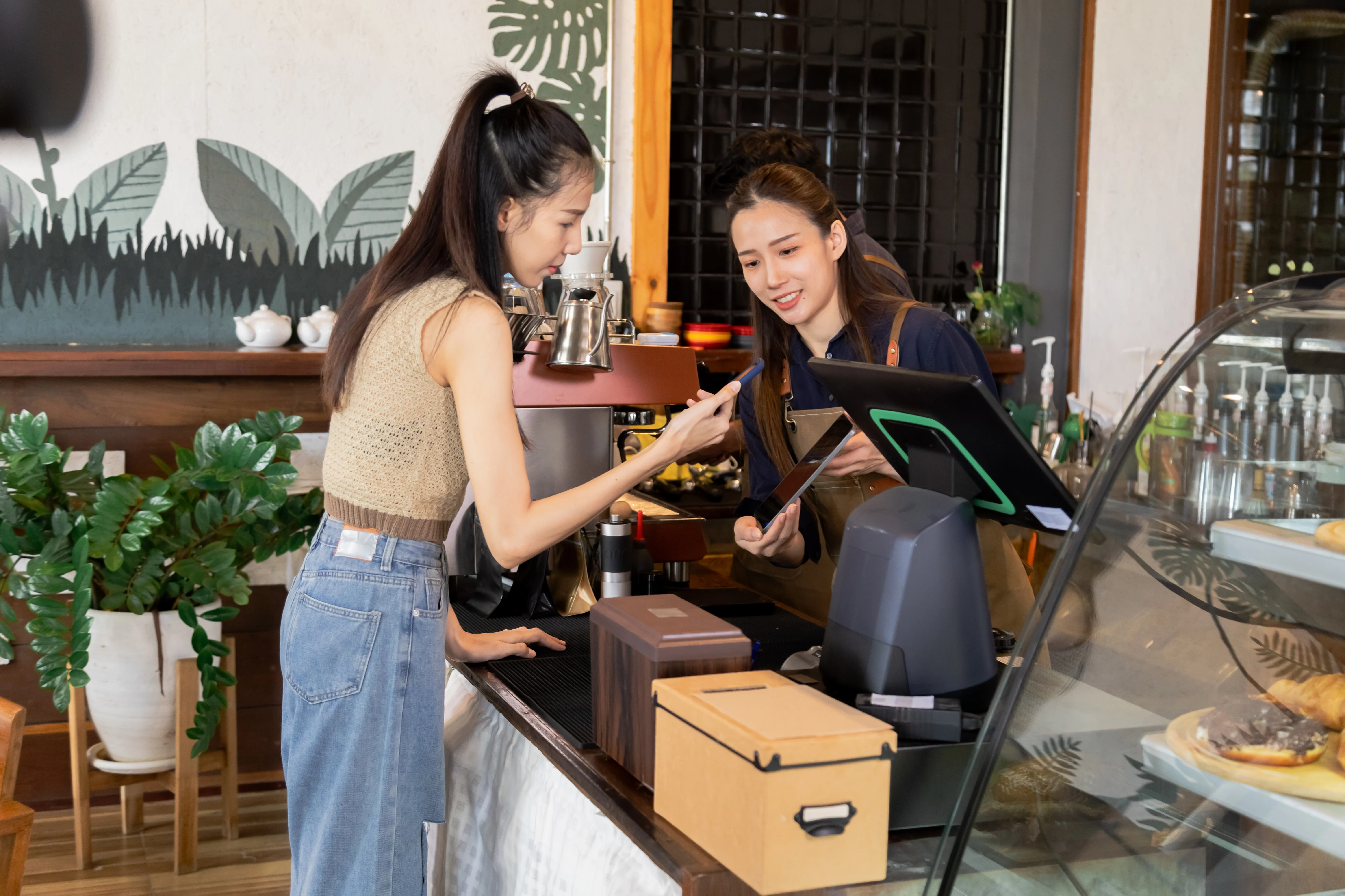 Smiling small business owner checking her phone at a laptop