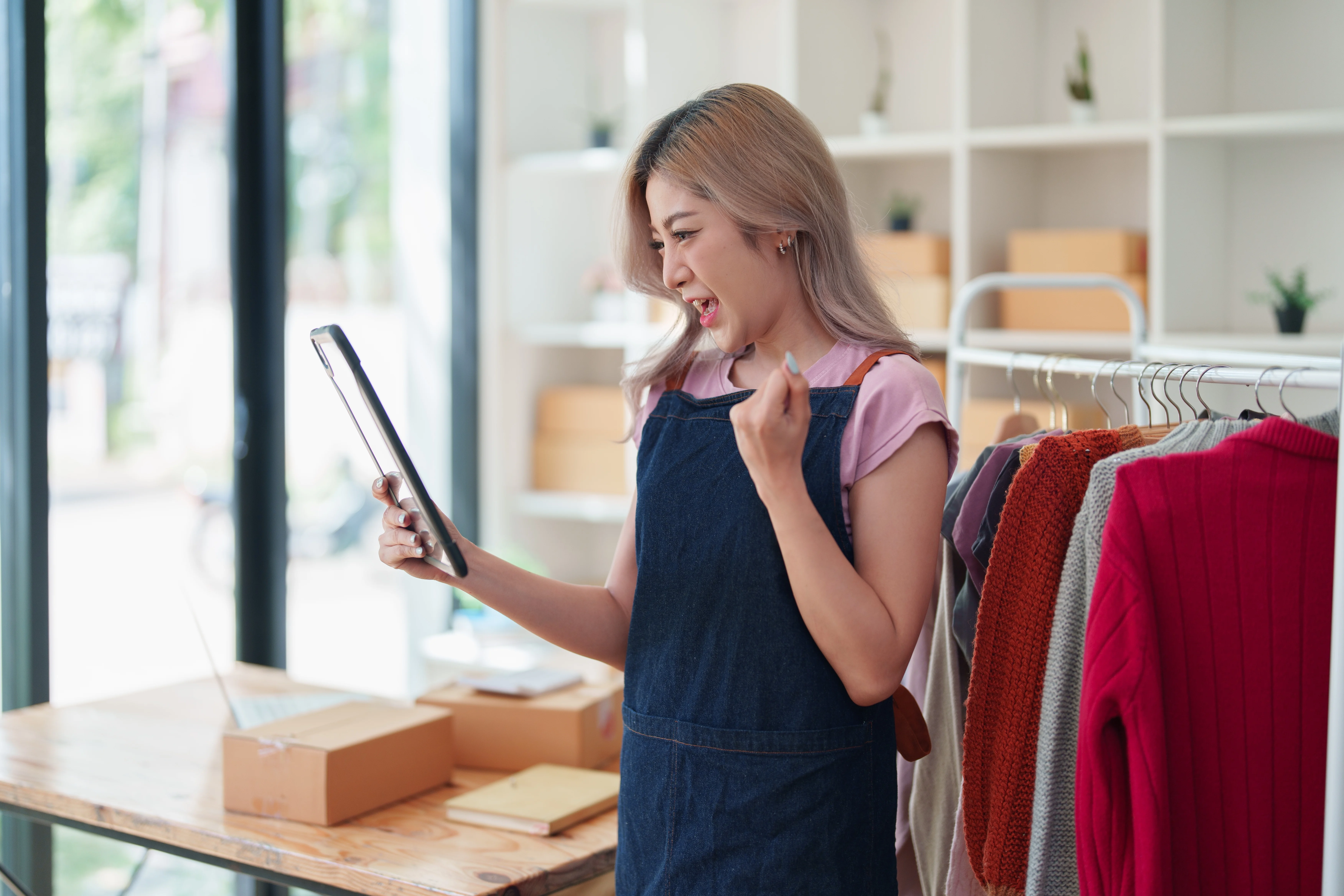 Smiling small business owner checking her phone at a laptop