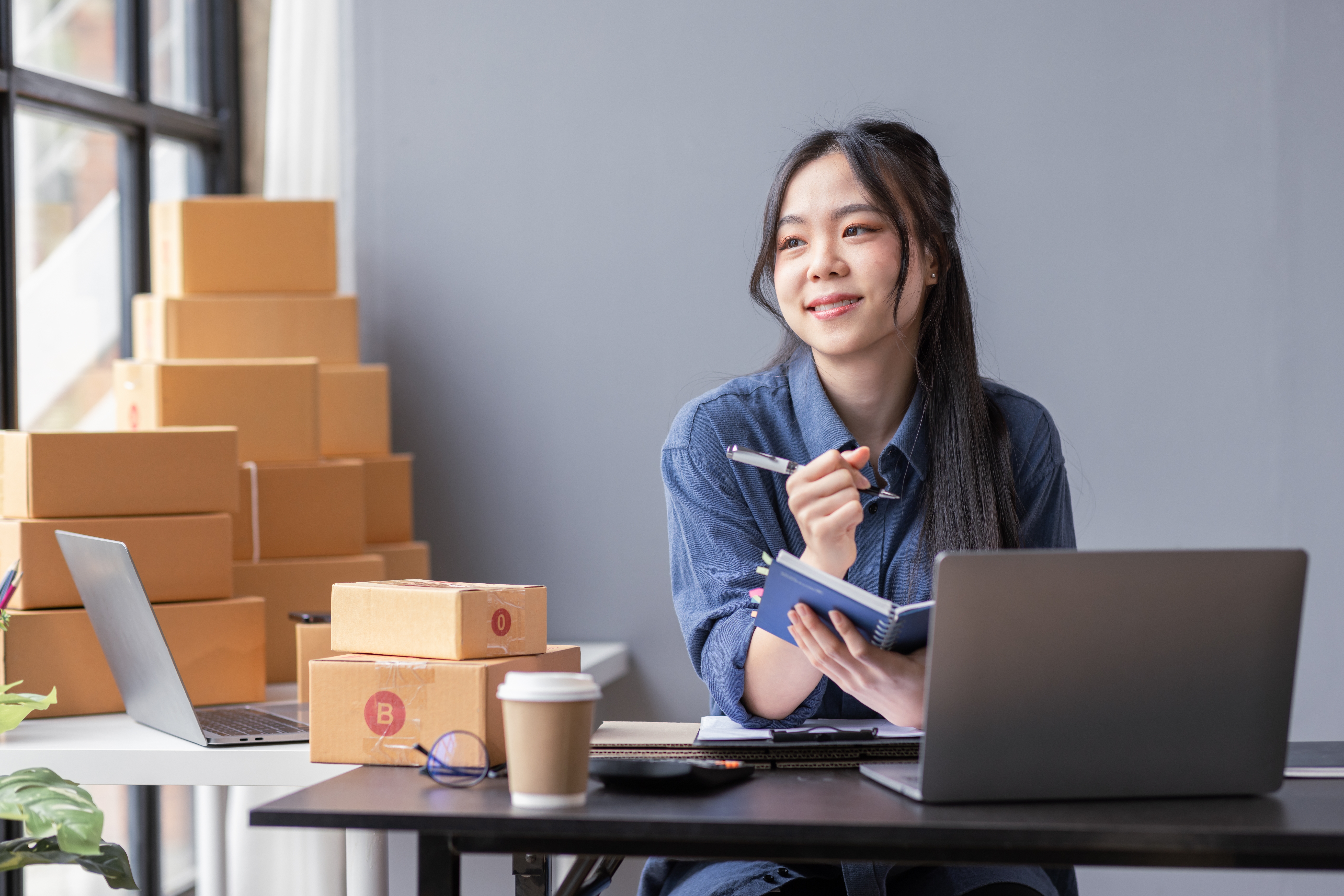 Smiling small business owner checking her phone at a laptop