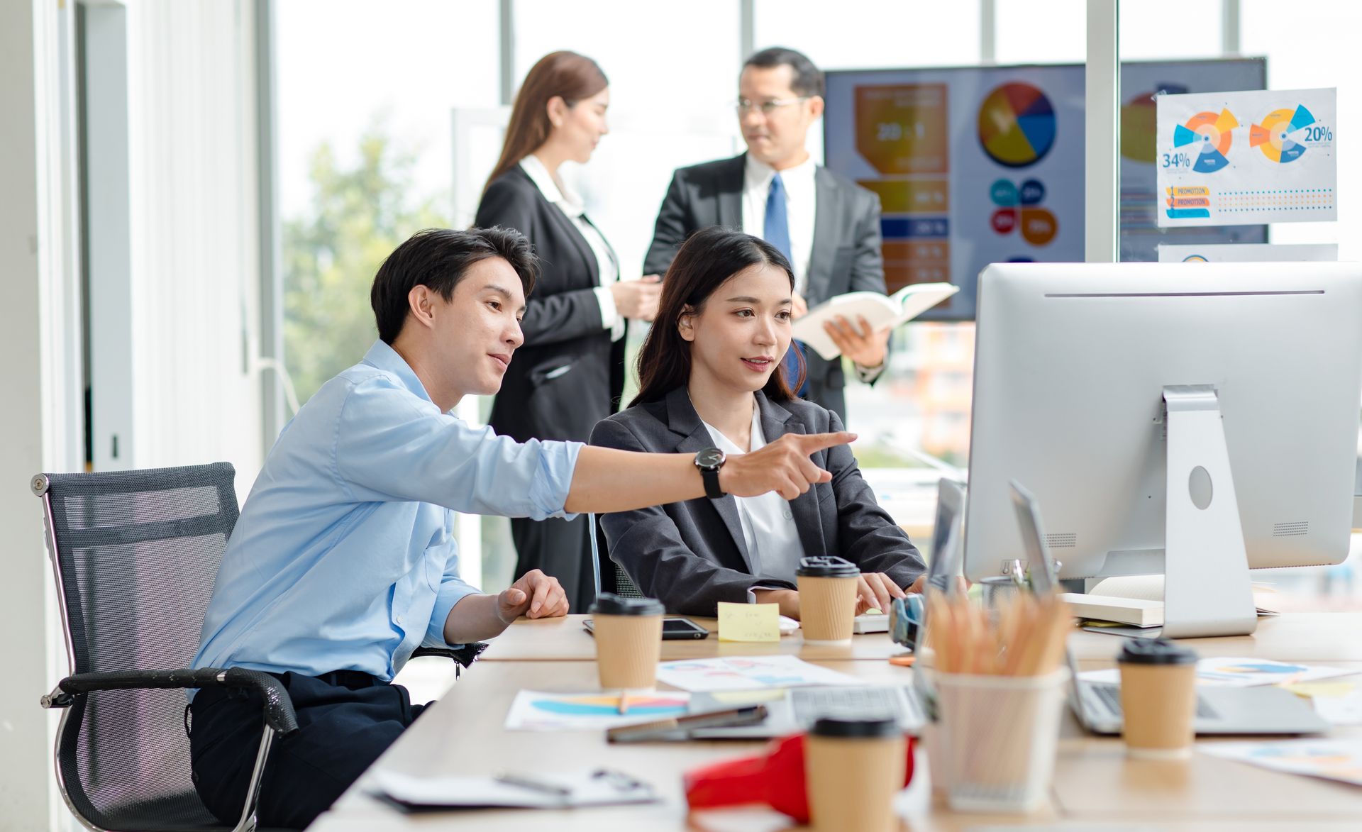 Business team pointing at a desktop screen during an office discussion