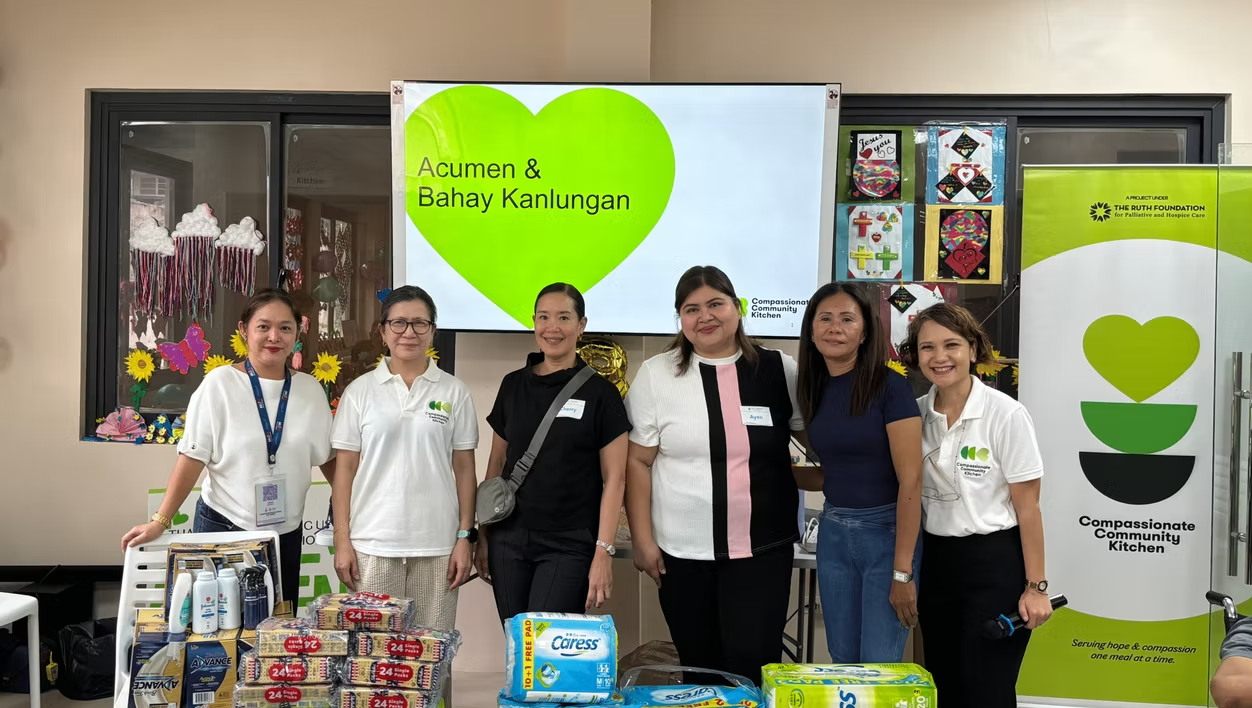 Group of Acumen team members posing at a community outreach booth