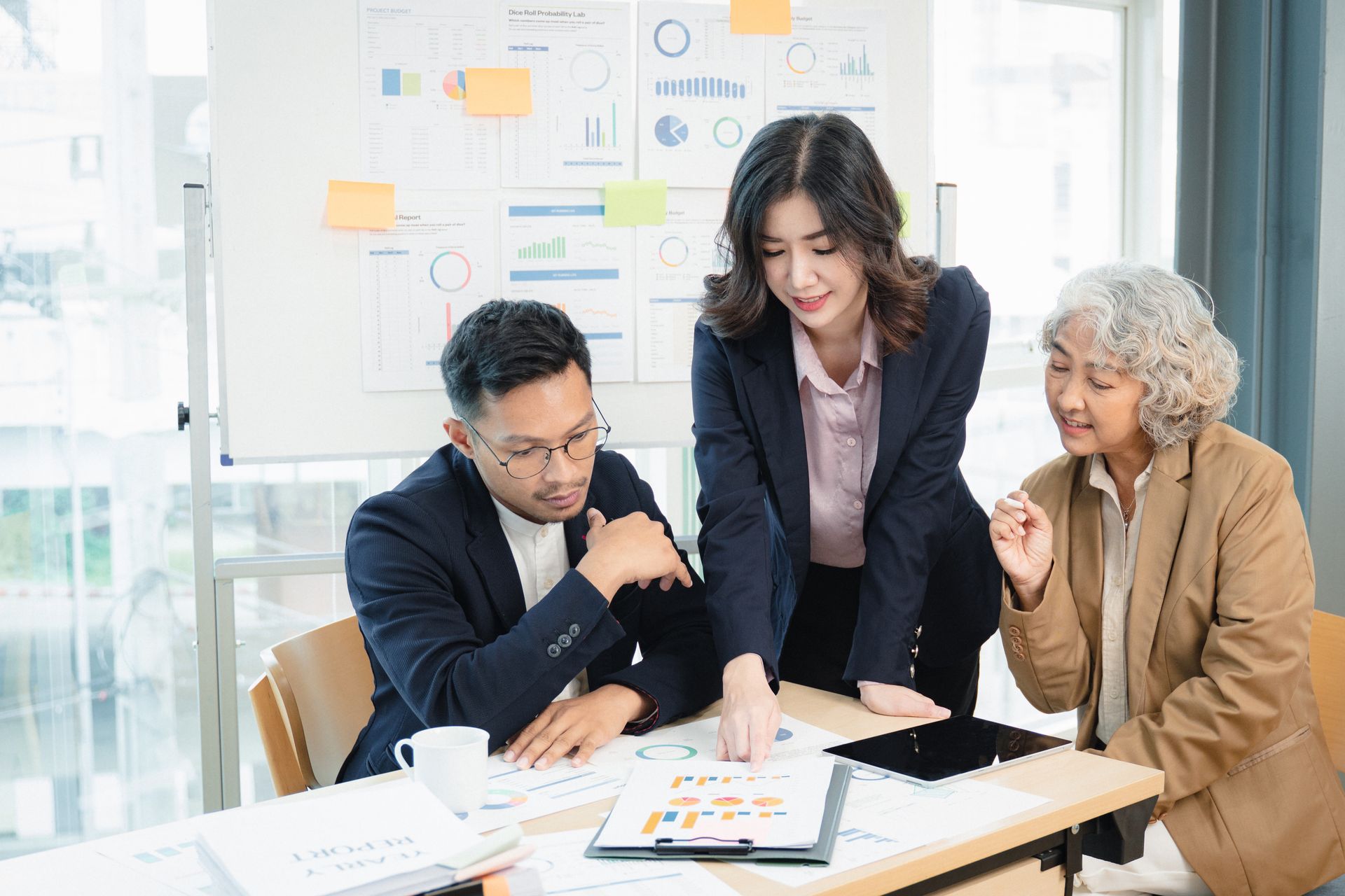 Three professionals reviewing documents together at a bright office table