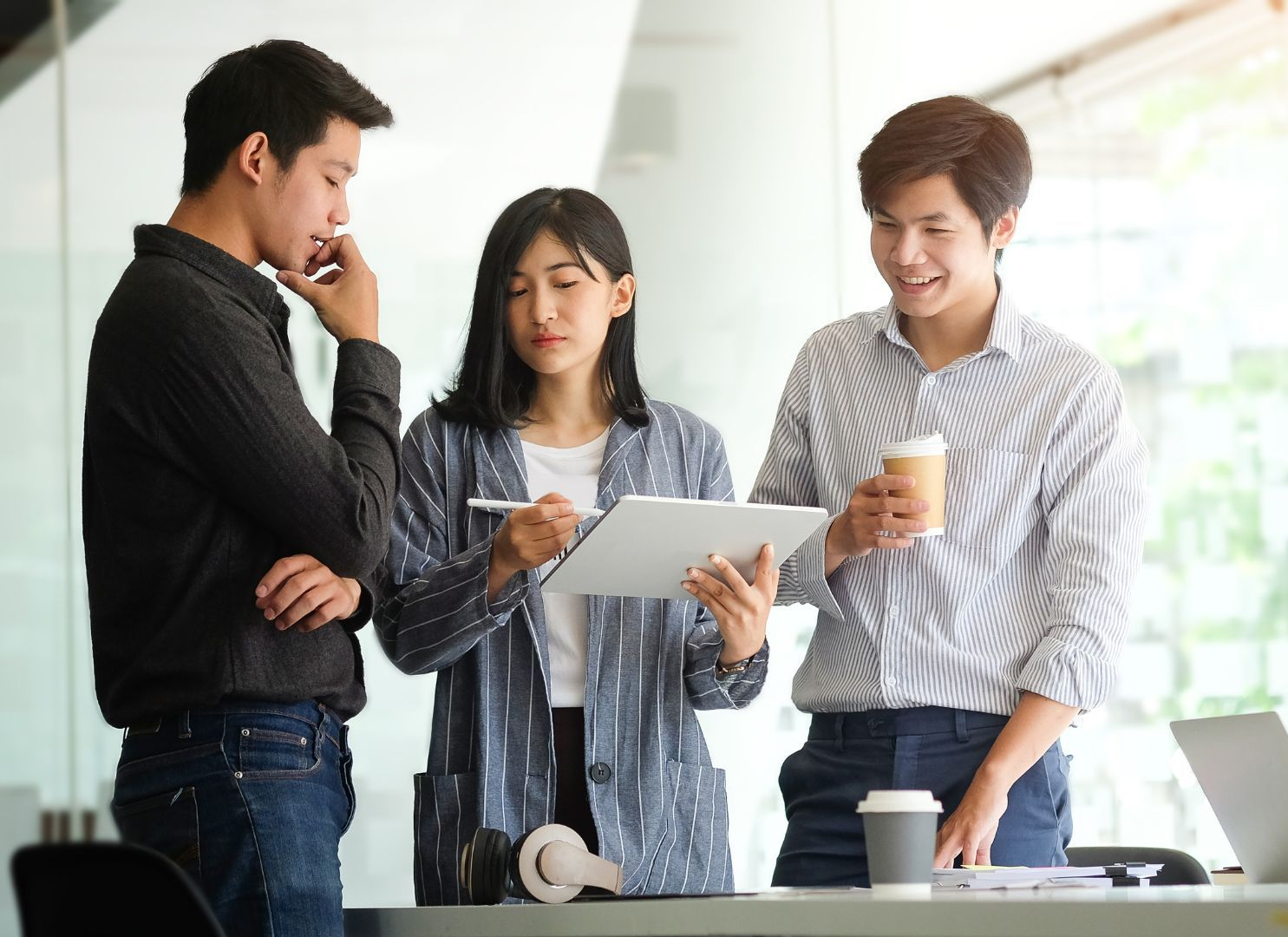Three colleagues reviewing a tablet together during an office conversation