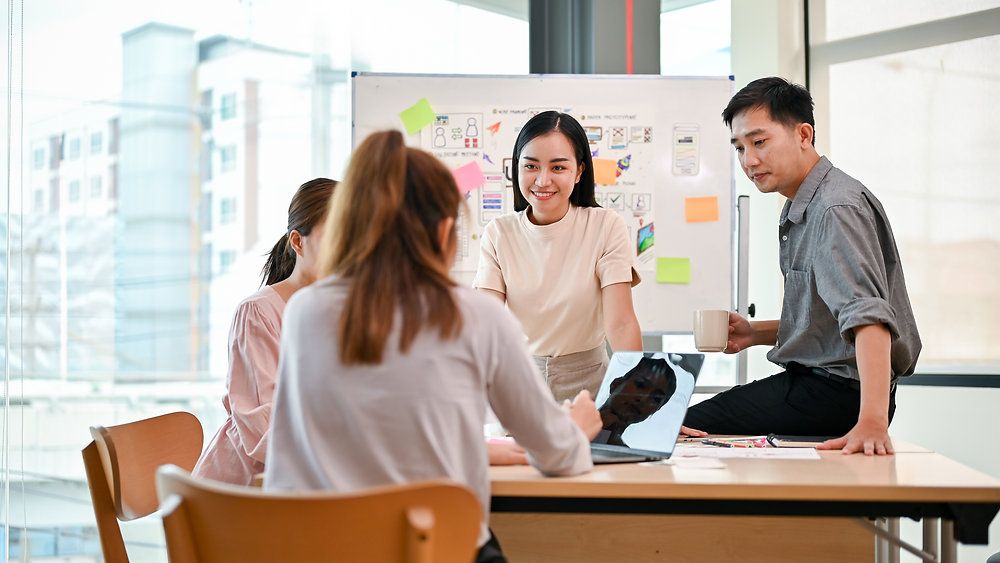Colleagues discussing over a laptop and sticky notes in a workshop setting