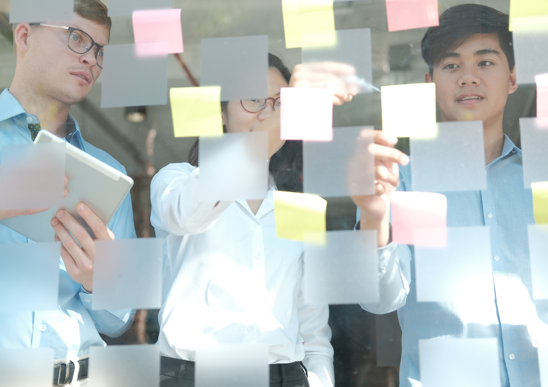 Team collaborating with sticky notes on a glass wall during a planning session