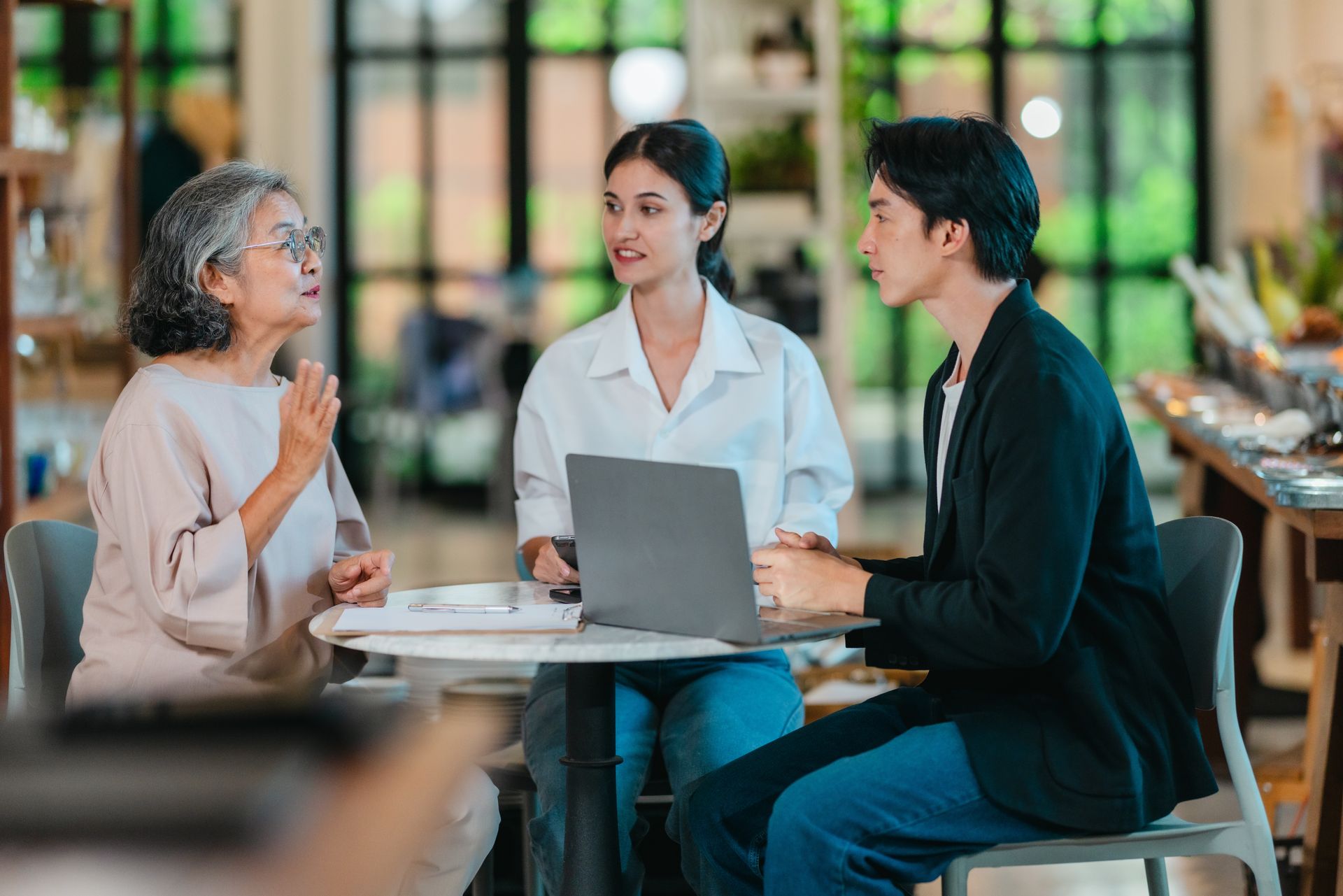 Multigenerational family working together at a laptop in a bright cafe