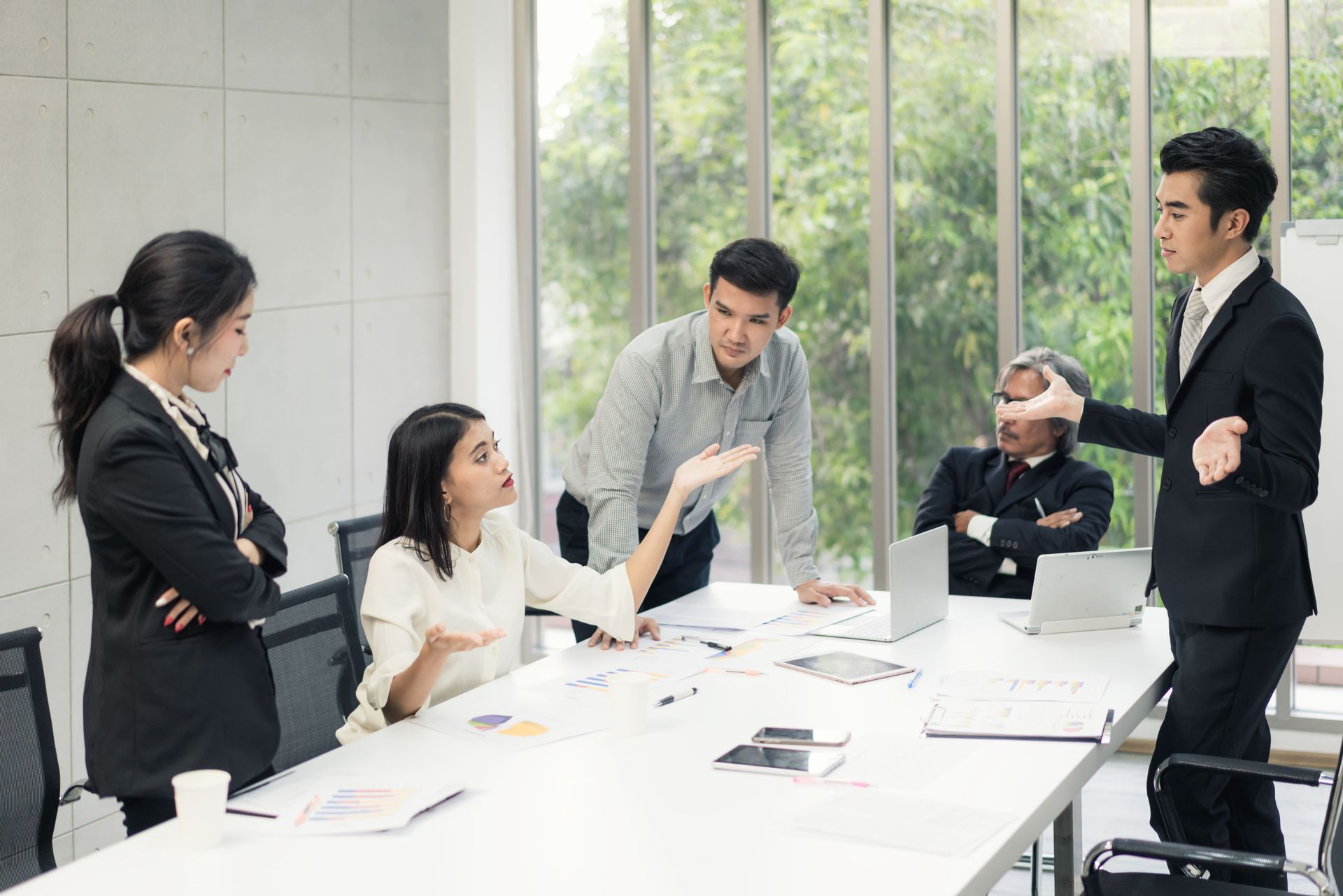Family business team in discussion around a conference table by a window